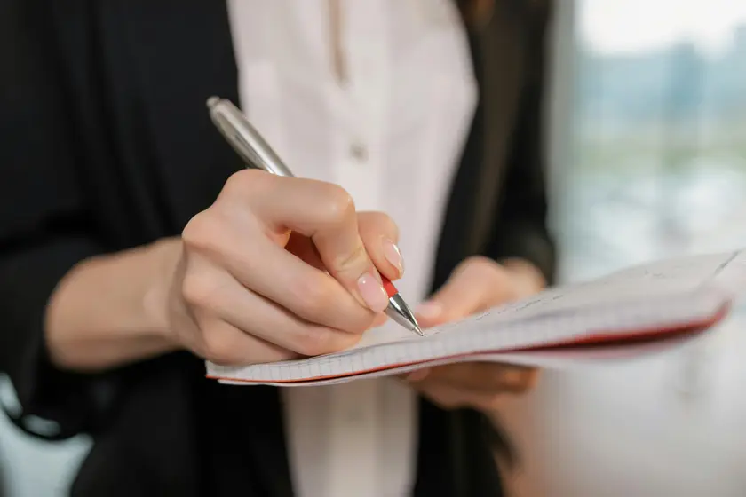 Main qui prend des notes dans un carnet — l'observation et l'analyse au cœur de l'audit.